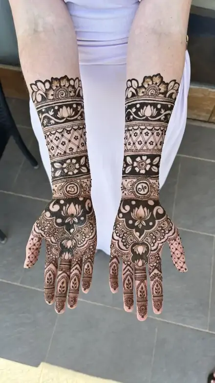 Full-arm bridal mehndi against a white lehenga